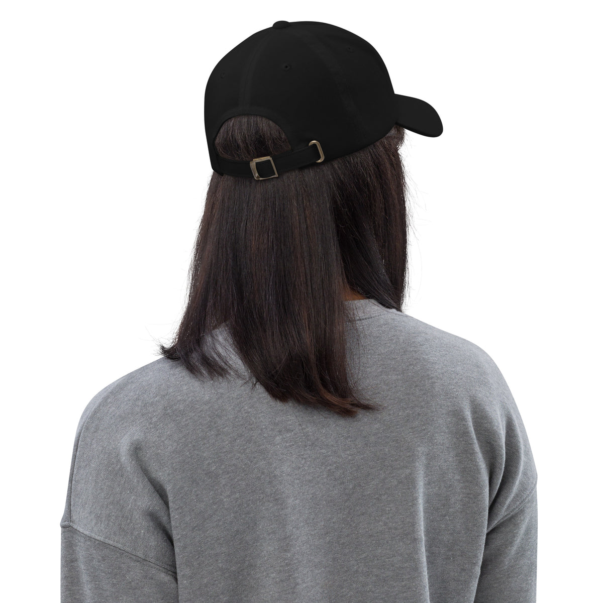Back view of a black unstructured dad hat with adjustable buckle strap and curved visor worn by person with long hair.