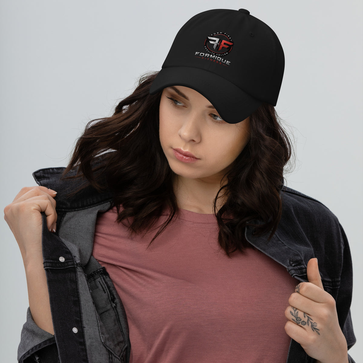 Woman wearing a black Formique Fitness low-profile dad hat with curved visor, unstructured 6-panel design, and embroidered logo.